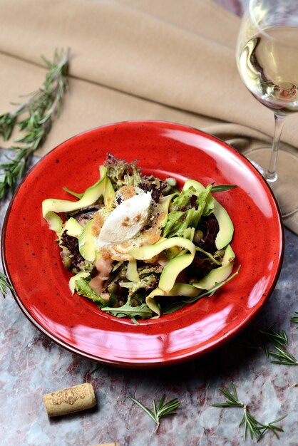 Salade au saumon, avocat et câpres sur une assiette rouge