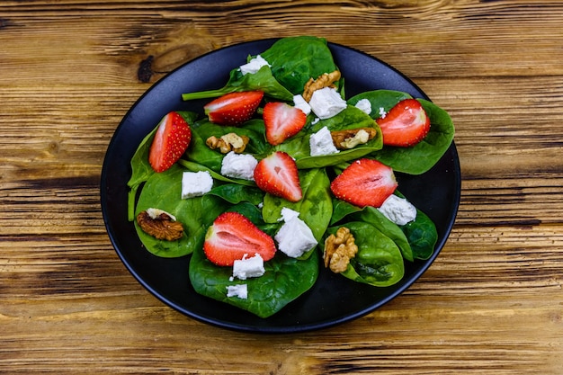 Salade aux feuilles d'épinards fromage feta noix et fraise sur une plaque noire