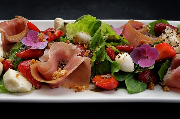 Salade aux fraises prosciutto et mozzarella sur fond noir