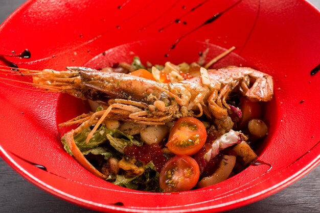 Une salade aux grosses crevettes, caviar et légumes sur fond de bois