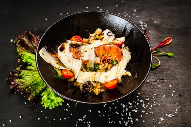 Une salade aux grosses crevettes et légumes sur fond noir