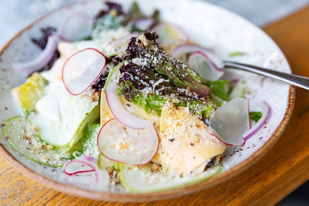 Salade aux herbes fraîches, radis et fromage sur une assiette.