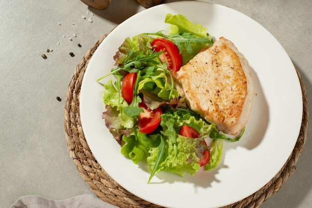 Salade aux légumes et poulet sur fond gris