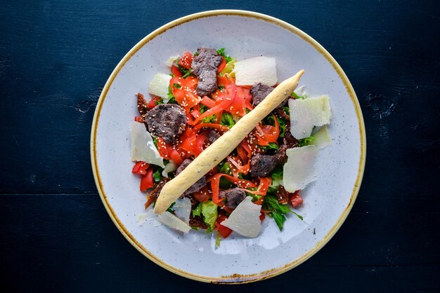 Salade aux légumes et veau et parmesan Sur un fond en bois Vue de dessus Espace libre pour le texte