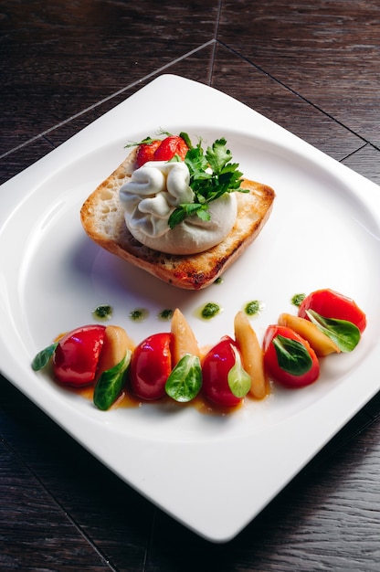 Salade aux tomates poire au miel et burrata au basilic et à l'huile d'olive sur une surface en bois