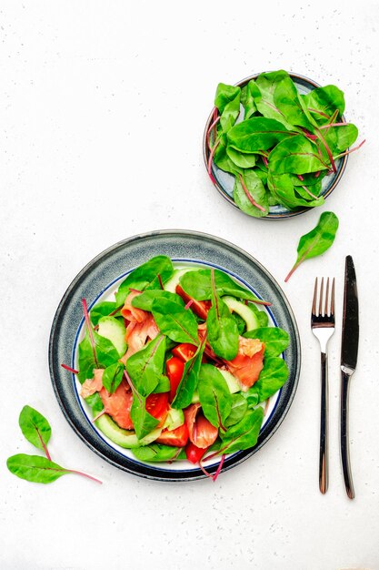 Salade d'avocat au saumon feuilles de betteraves tomates radicchio vinaigrette au citron et à l'huile d'olive pour régime céto et carte basse Vue de dessus sur fond gris