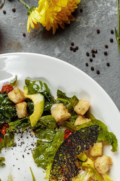 Salade d'avocat aux bébés épinards et à la grenade sur une plaque noire sur un backgro en ardoise ou en béton