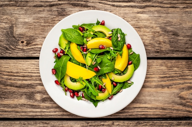 salade d'avocat, roquette, épinards, grenade, graines sur fond de bois