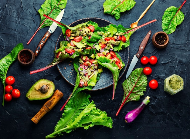 Salade d'avocat, tomate avec sauce à l'ail dans des feuilles de blettes. Salade de vitamines d'été dans l'assiette. Salade saine