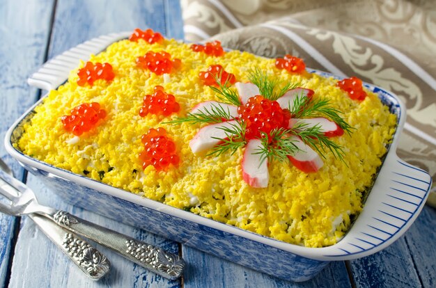 Salade de bâtonnets de crabe décorée de caviar rouge