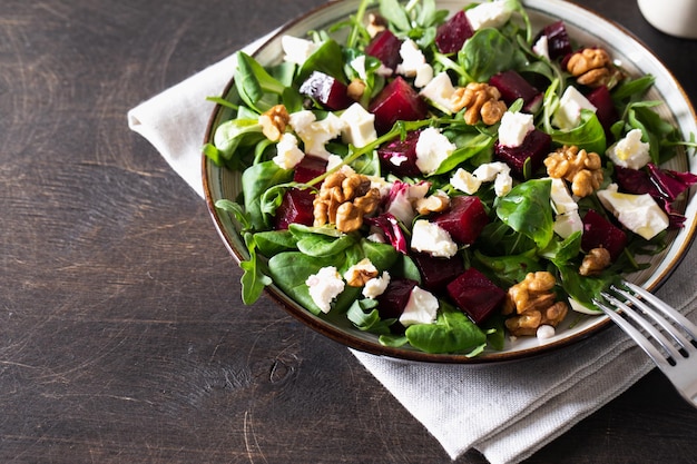 Salade de betteraves ou de betteraves avec fromage à pâte molle de roquette fraîche et noix sur assiette vinaigrette et épices