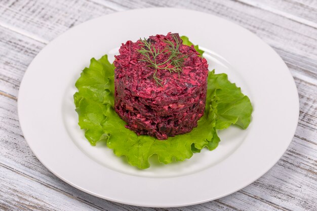 Salade de betteraves, prunes séchées, noix sur une plaque blanche, gros plan