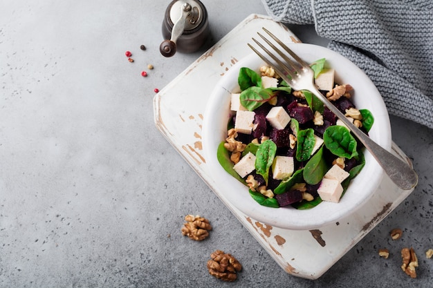 Salade de bettes, roquette, betterave, ricotta et noix à l'huile d'olive dans une vieille assiette en céramique sur une surface grise ou béton vieilli. Mise au point sélective. Vue de dessus.