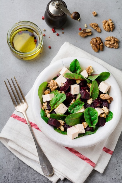 Salade de bettes, roquette, betterave, ricotta et noix à l'huile d'olive dans une vieille plaque en céramique sur une surface de béton gris