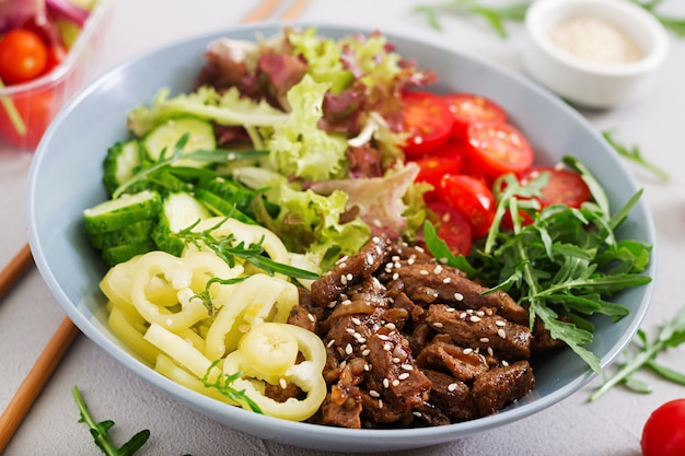 Salade de bœuf teriyaki et légumes frais - tomates, concombres, paprika, roquette et laitue dans un bol.