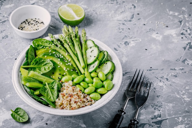 Salade de bol de bouddha végétarien vert sain avec légumes frais et quinoa épinards avocat asperges concombre haricots edamame aux graines de sésame sur fond gris