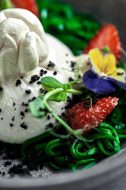 Salade de burrata aux fraises et aux algues sur fond gris Salade au fromage buratta sur une plaque grise et gros plan de fond en marbre de béton