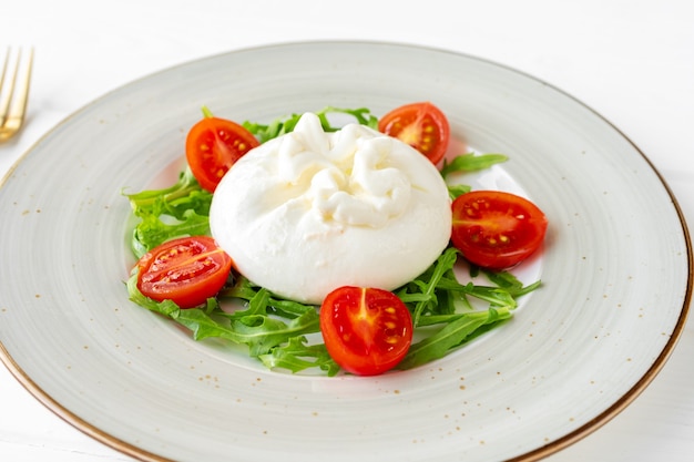 Salade de burrata et tomates cerises sur fond de bois blanc