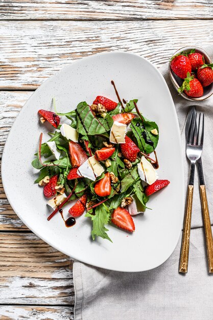 Salade de camembert, fraises, noix, blettes et roquette. Fond blanc. Vue de dessus.