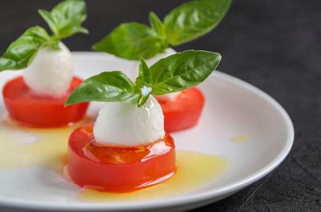 Salade caprese aux tomates mûres et mozzarella aux feuilles de basilic frais. Nourriture italienne.