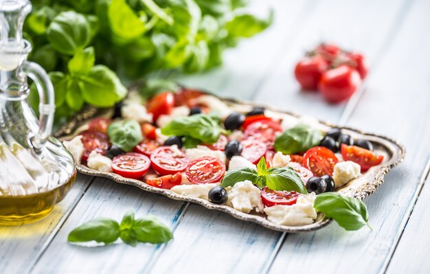 Salade caprese avec fromage mozzarella tomates mûres olives et feuilles de basilic. Repas sain italien ou méditerranéen.