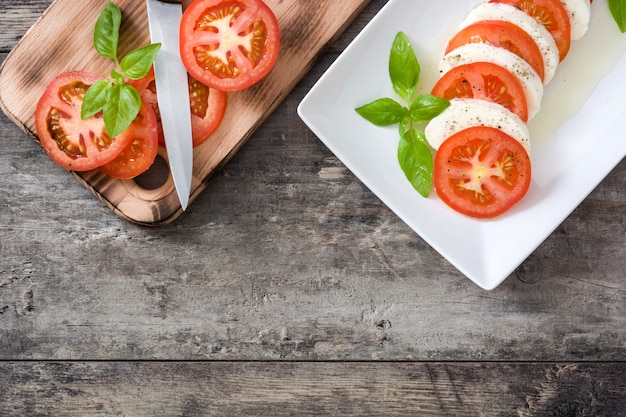 Salade Caprese et ingrédients sur bois