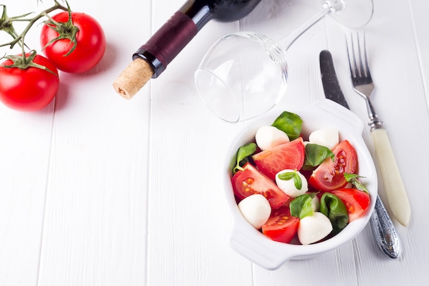 Salade Caprese italienne aux tomates fraîches, avec des tranches de tomates mûres et du mini fromage mozzarella