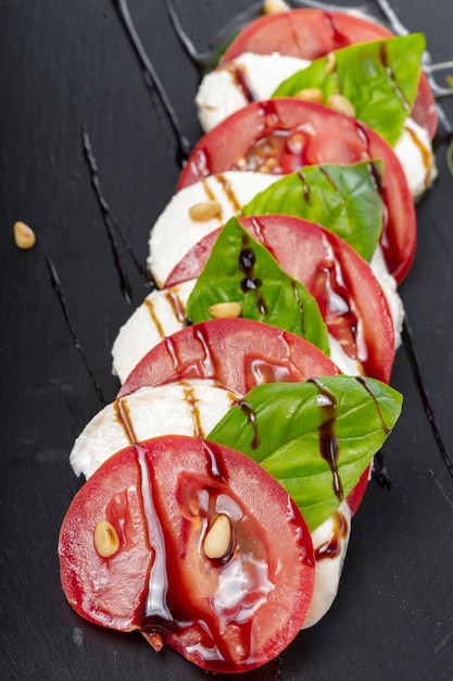 Salade caprese italienne fraîche avec mozzarella et tomates sur plaque sombre