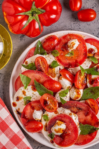 Salade caprese italienne avec tomates tranchées, fromage mozzarella, basilic, huile d'olive, vinaigre balsamique. Vue de dessus, copiez l'espace.