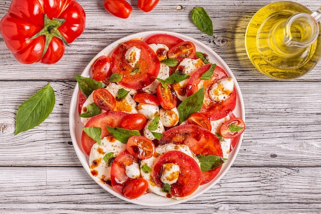 Salade caprese italienne avec tomates tranchées, fromage mozzarella, basilic, huile d'olive, vinaigre balsamique. Vue de dessus, copiez l'espace.