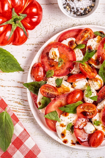 Salade caprese italienne avec tomates tranchées, fromage mozzarella, basilic, huile d'olive, vinaigre balsamique. Vue de dessus, copiez l'espace.