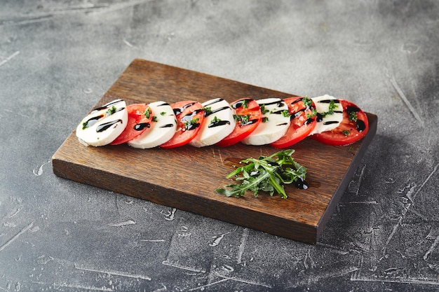 Salade caprese avec tomates au fromage mozarella et basilic sur une planche à découper en bois