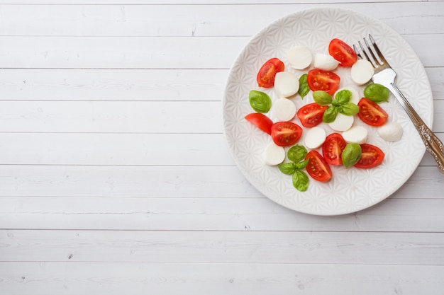 Salade Caprese de tomates, fromage mozzarella et basilic sur une assiette blanche. Cuisine italienne. Espace de copie