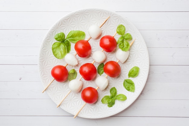 Salade Caprese de tomates, fromage mozzarella et basilic sur une assiette blanche. Cuisine italienne.