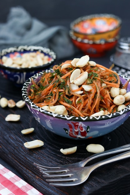 Salade de carottes aux arachides dans un style oriental situé dans un bol bleu sur un fond sombre