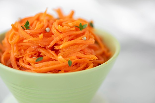 Salade de carottes épicée de style coréen avec des épices et des herbes dans un gros plan de bol vert