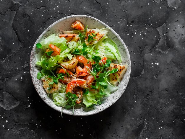 Salade César aux crevettes grillées sur une vue de dessus de fond sombre