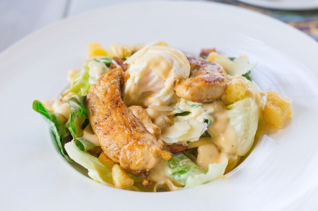 La salade César aux légumes verts frais est mélangée à un blanc de poulet grillé et à du pain croustillant