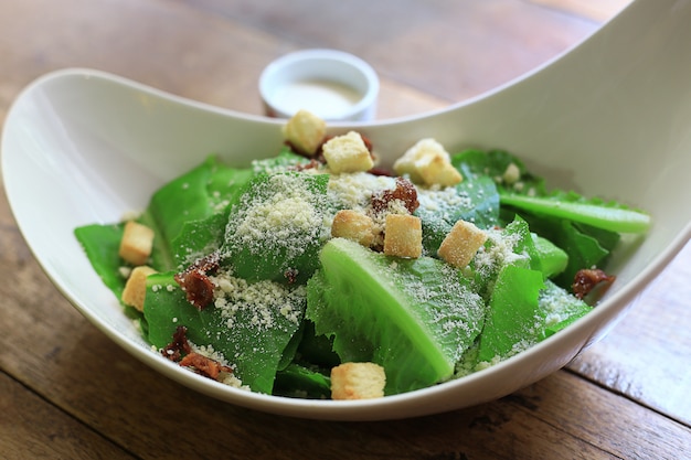 Salade César Un bol de déjeuner santé. avec sauce dans des tasses sur fond de table en bois.