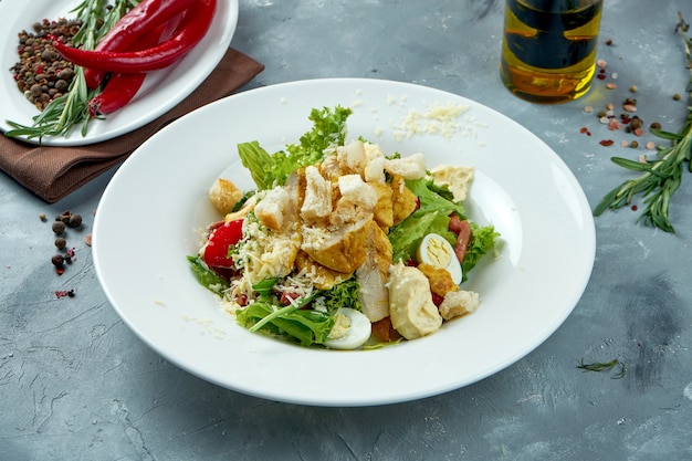 Salade César classique avec croûtons, poulet, parmesan et sauce dans une assiette blanche