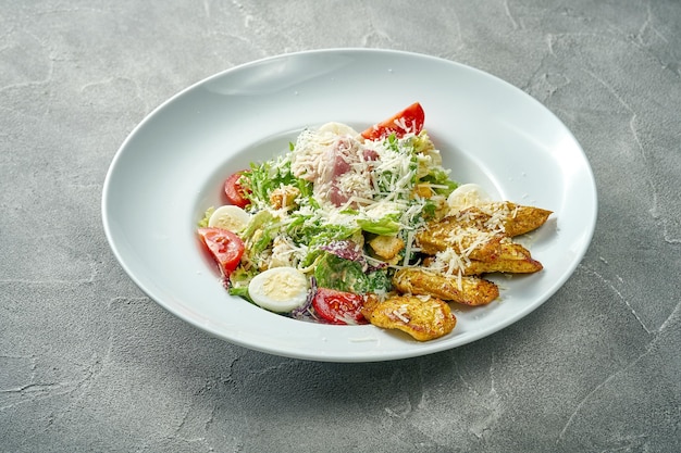 Salade césar classique avec sauce poulet grillé et légumes dans une assiette blanche Fond de béton