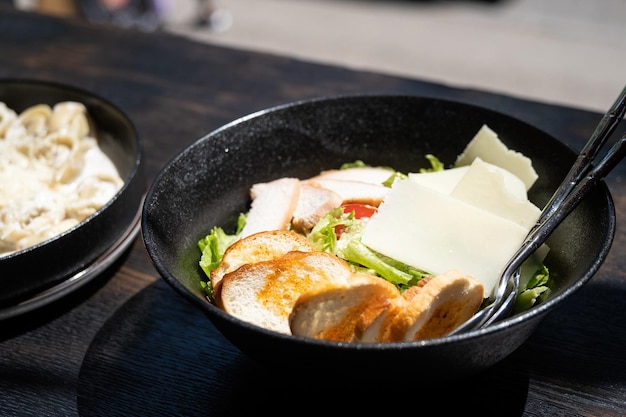 Salade César dans un bol noir sur le comptoir du restaurant près de la fenêtre