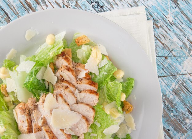 Photo salade césar avec du poulet et des légumes verts sur une table en bois