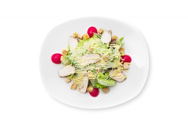 Salade César fraîche au poulet sur une assiette blanche isolée.