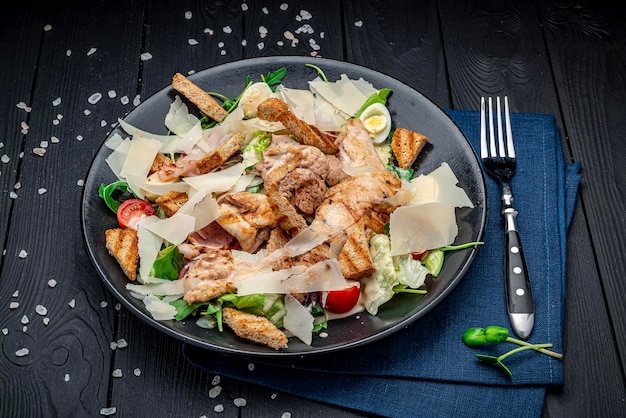 Salade césar fraîche dans une assiette blanche sur une table en bois foncé Vue de dessus