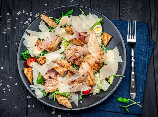 Salade césar fraîche dans une assiette blanche sur une table en bois foncé Vue de dessus