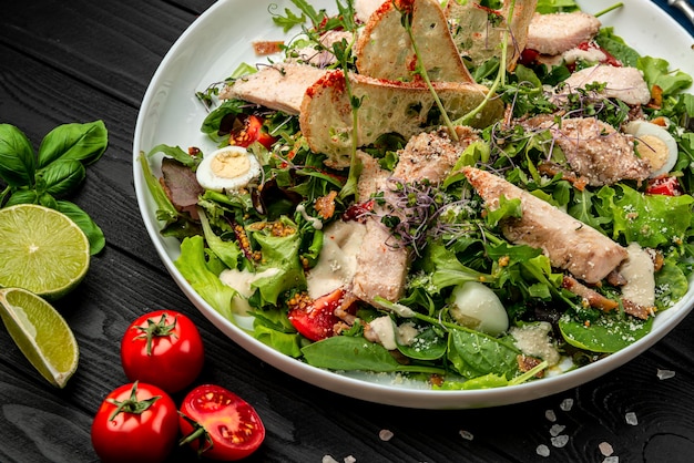 Salade César fraîche dans une assiette blanche sur une table en bois sombre Vue de dessus Servir de la nourriture dans un restaurant Concept d'aliments sains Photo pour le menu