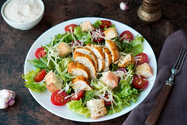 Salade César avec poitrine de poulet, croûtons et sauce parmesan sur une table en bois