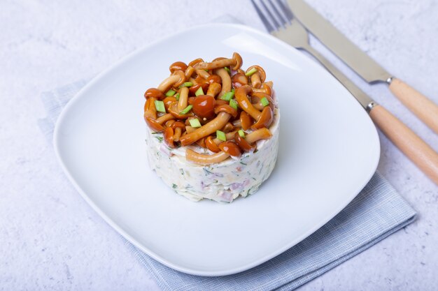 Salade de champignons (champignon de miel), jambon, pommes de terre, fromage et mayonnaise. Panier de salade de champignons salade russe traditionnelle. Mise au point sélective, gros plan.