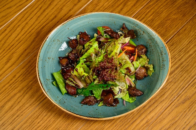 Photo salade de champignons frits, tomates et laitue sur une table en bois, vue du dessus